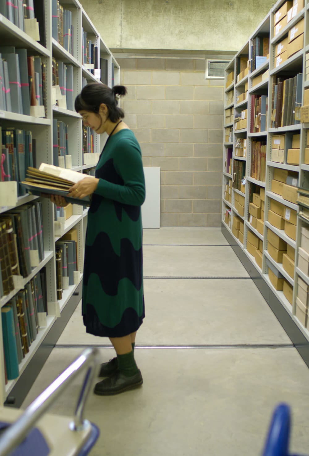 This image shows artist Anushka Tay researching the Miscellaneous Reports volumes inside the Archive store at the Royal Botanical Gardens, Kew