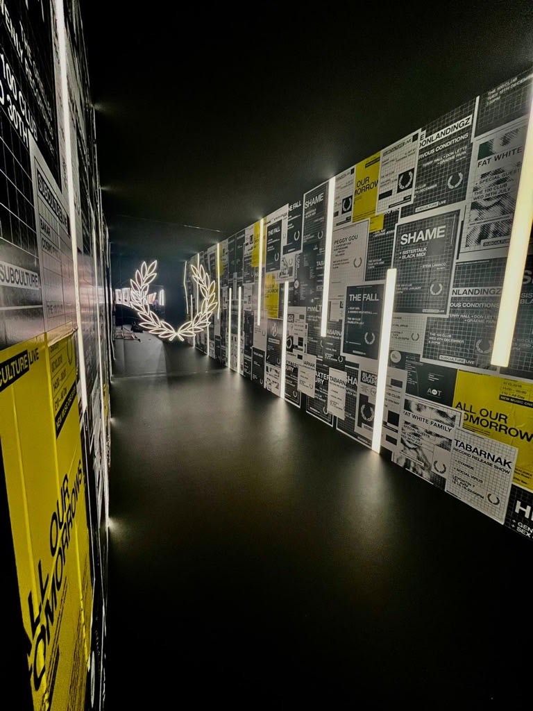 Exhibition display of Fred Perry in gallery depicting a small corridor lined with posters
