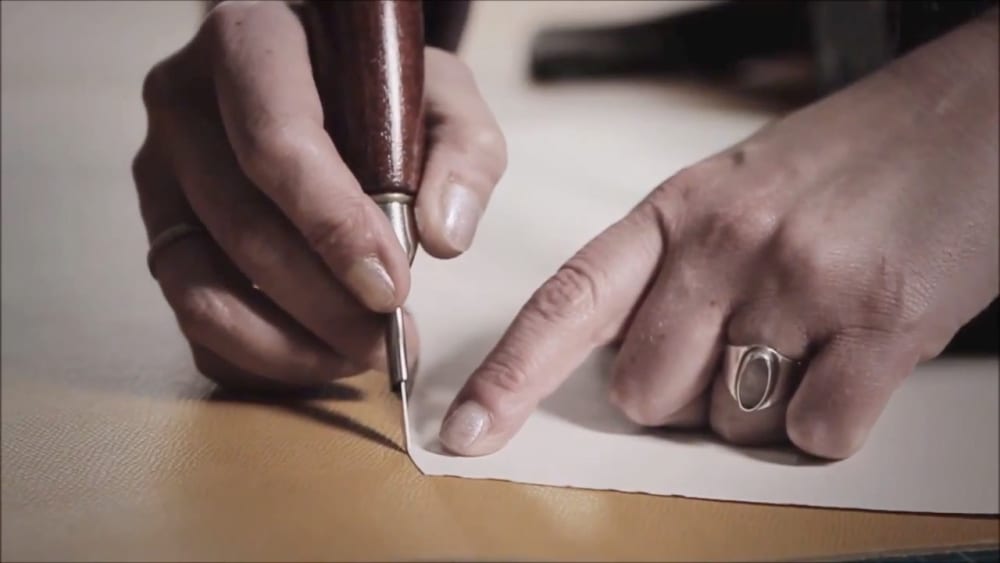 Woman's hands crafting leather goods.