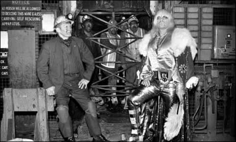 blackand white image of a punk wrestler stood necxt to a dirty coal miner