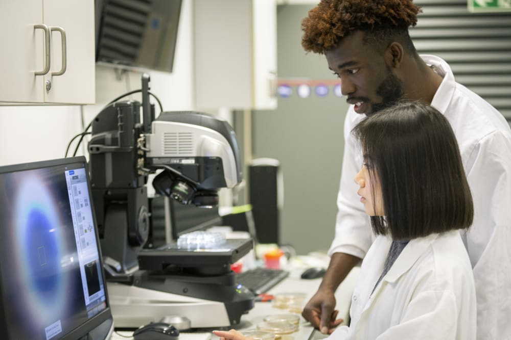 Students working in a lab wearing white coats 