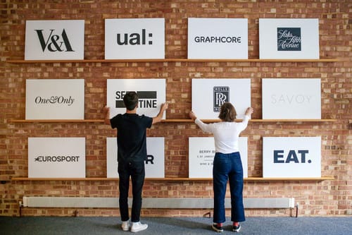Two students stood in front of a wall of company logos