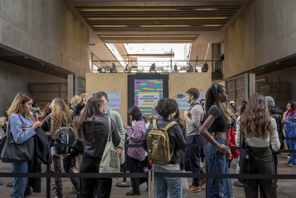 A line of people wait at the Creative Opportunities job fair registration desk