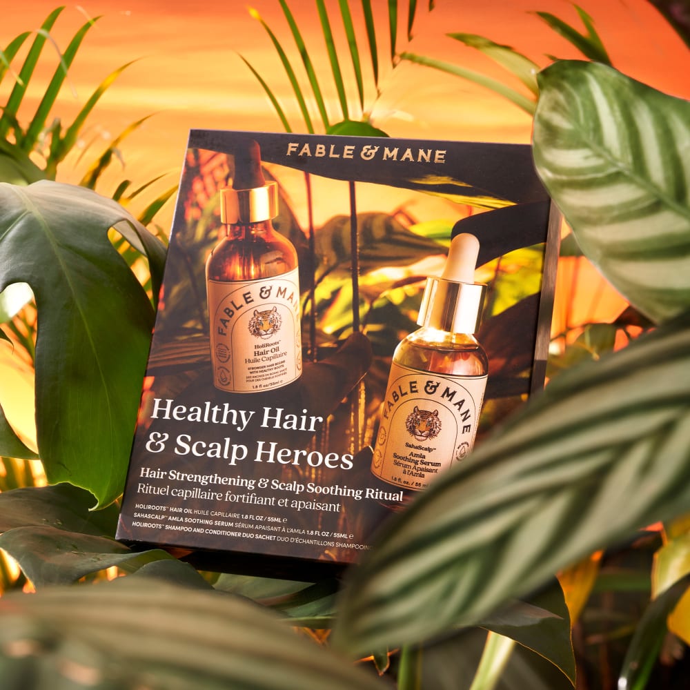 An advertisement for haircare products surrounded by foliage, with an orange sunset backgdounr