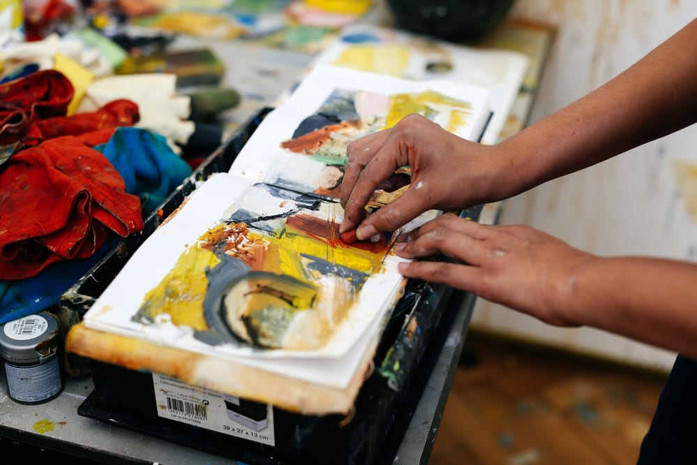 The hands of a Fine Art student working on their sketchbook in the studio.