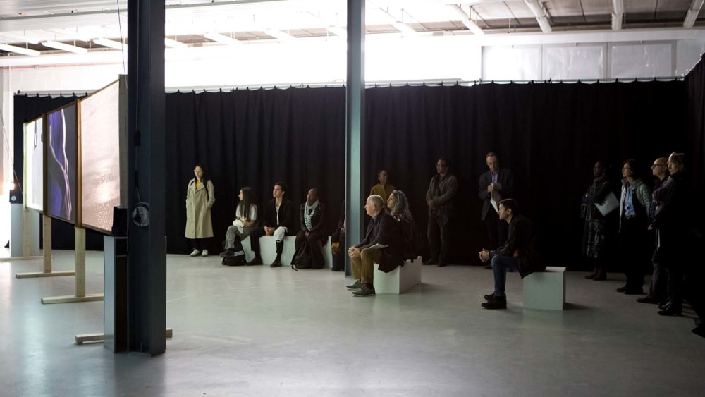 Audience sitting in Chelsea Triangle Space watching a video installation