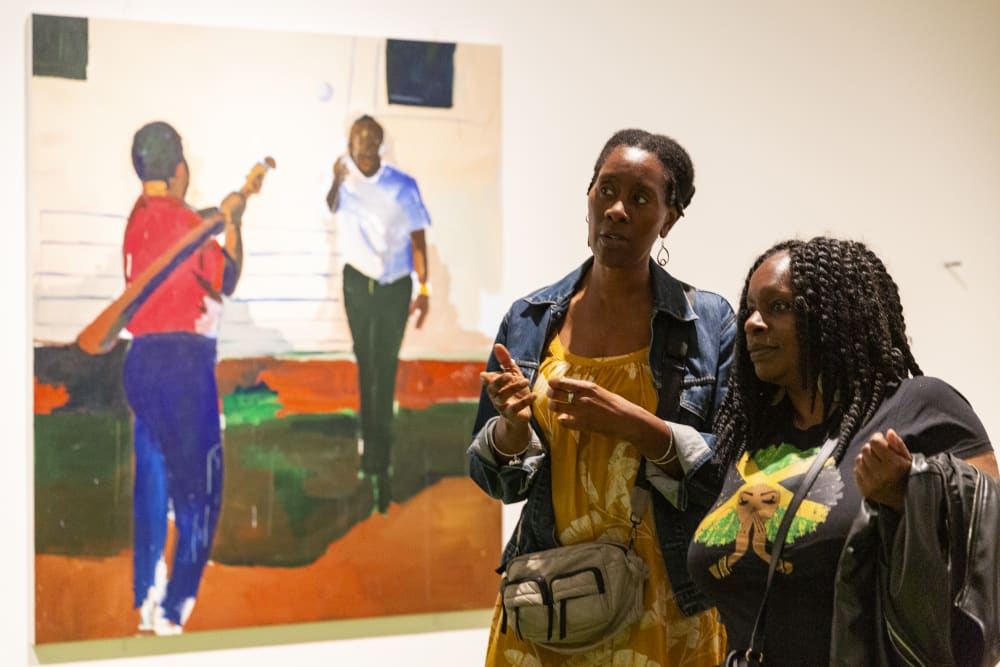Guests discussing a piece of work. In the background is a large painting