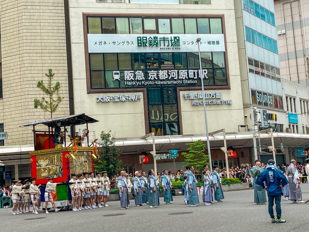 crowd outside a building in Japan with a red and gold float