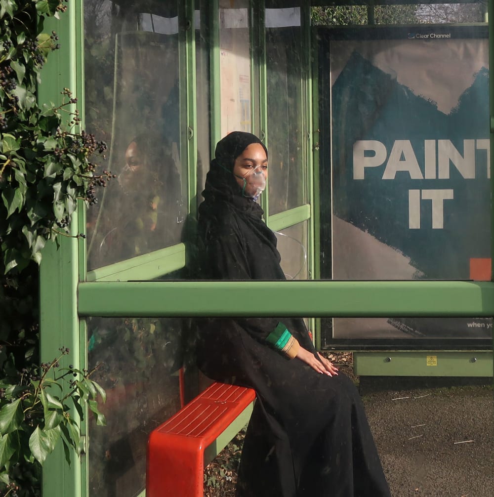 woman in hijab at bus stop wearing mask
