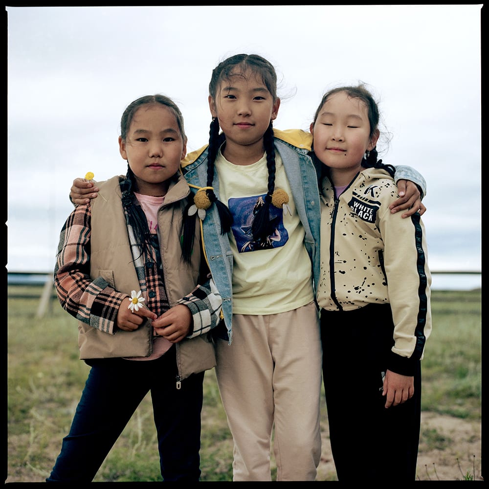 Three young girls smile at the camera.