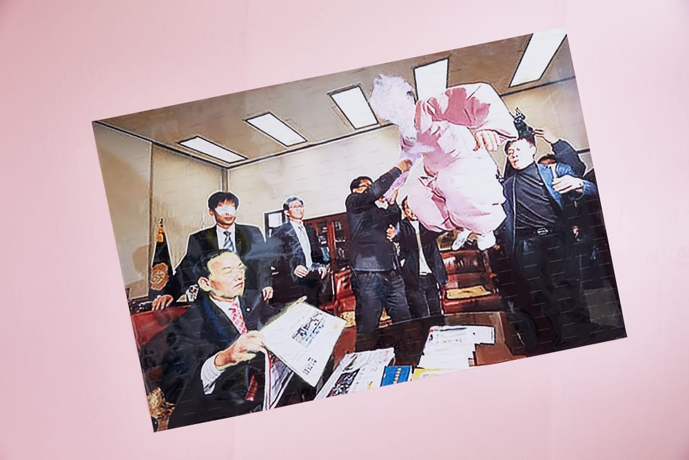 Damaged photo of business men hung up on pink wall by student Jit Seo.