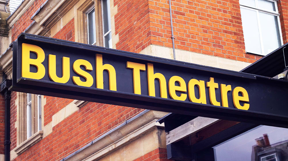 A sign for Bush Theatre. Yellow text on a black background.