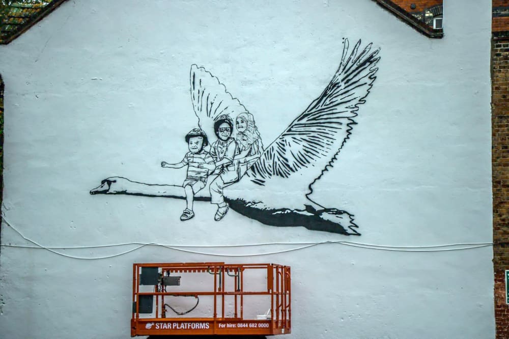 A mural of three children riding on the back of a giant flying goose 