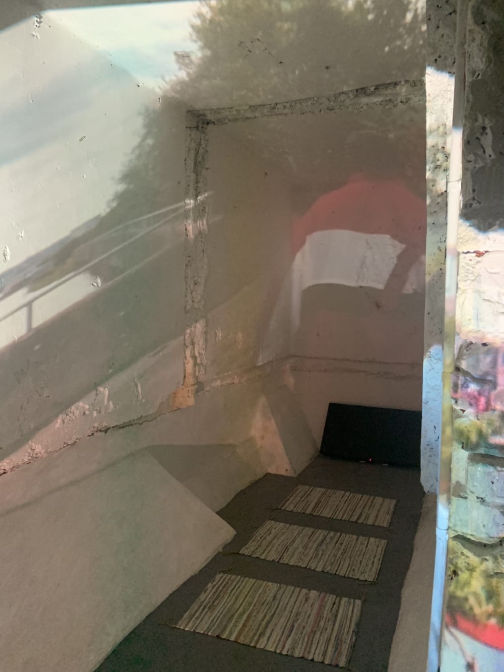 Narrow gallery space with video projection and matts on the floor