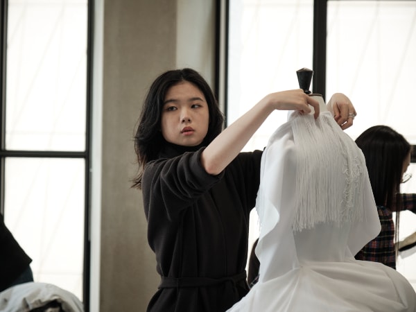 Student adding bridalwear to a mannequin.