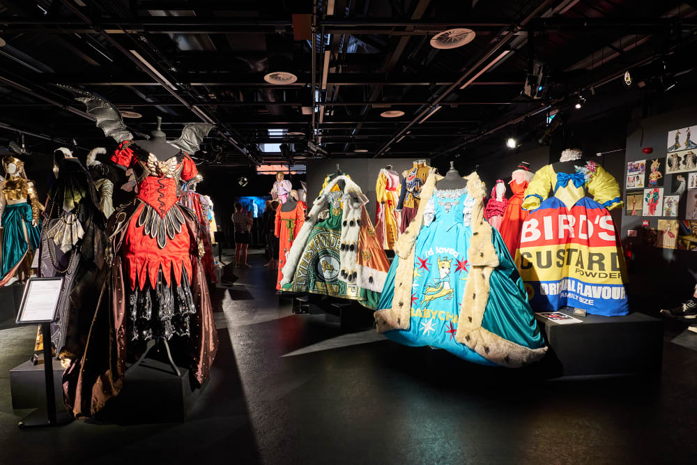 A vibrant graduate showcase display featuring a variety of ornate theatrical costumes on mannequins.