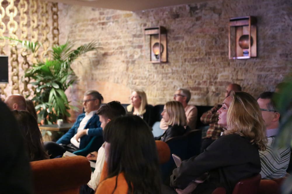 People are seated, listening to a speech and not facing the camera