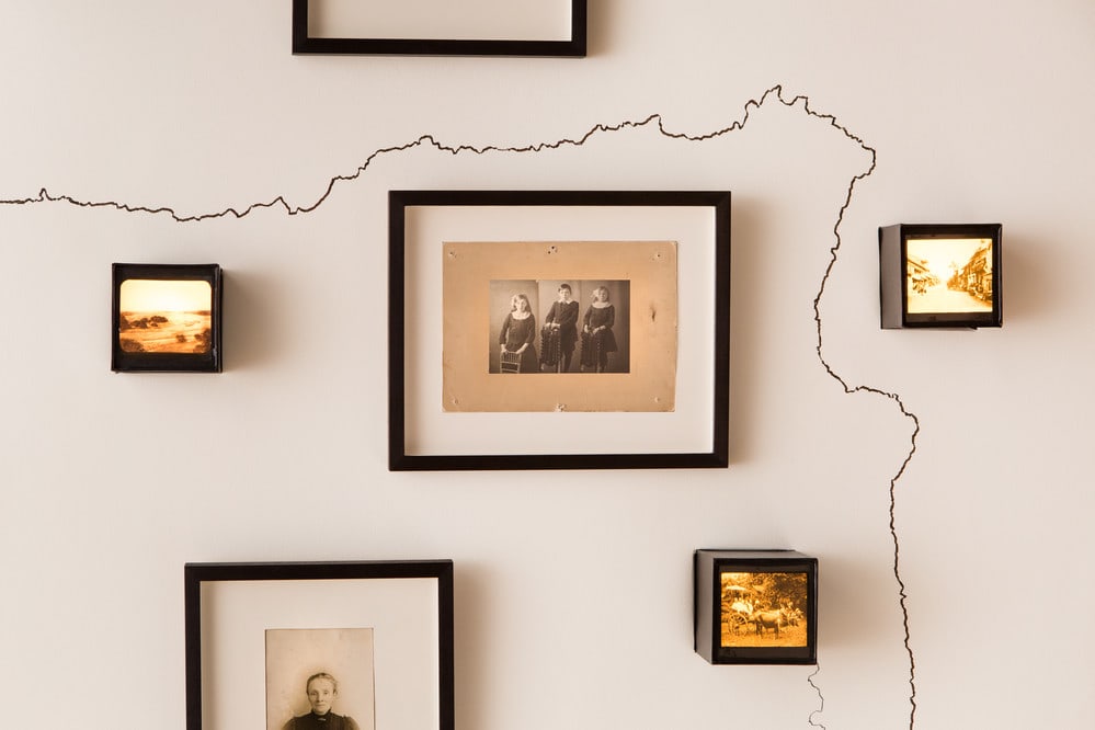 A gallery wall featuring six different black framed pictures. The white wall features a large crack running through the framed pictures.