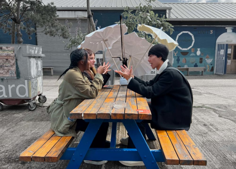 Three students sitting on a picnic table