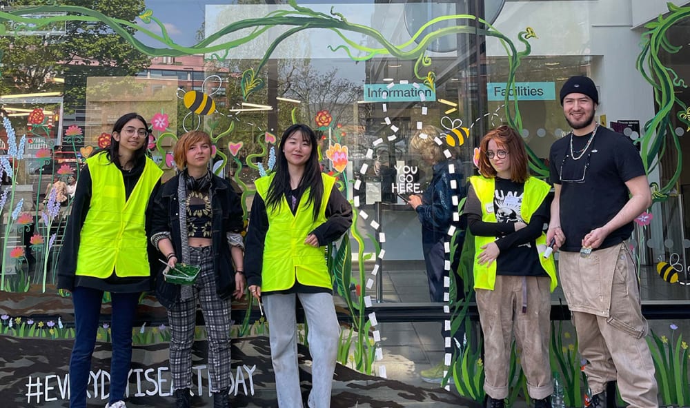 Image of people in high-vis jackets outside a window mural.
