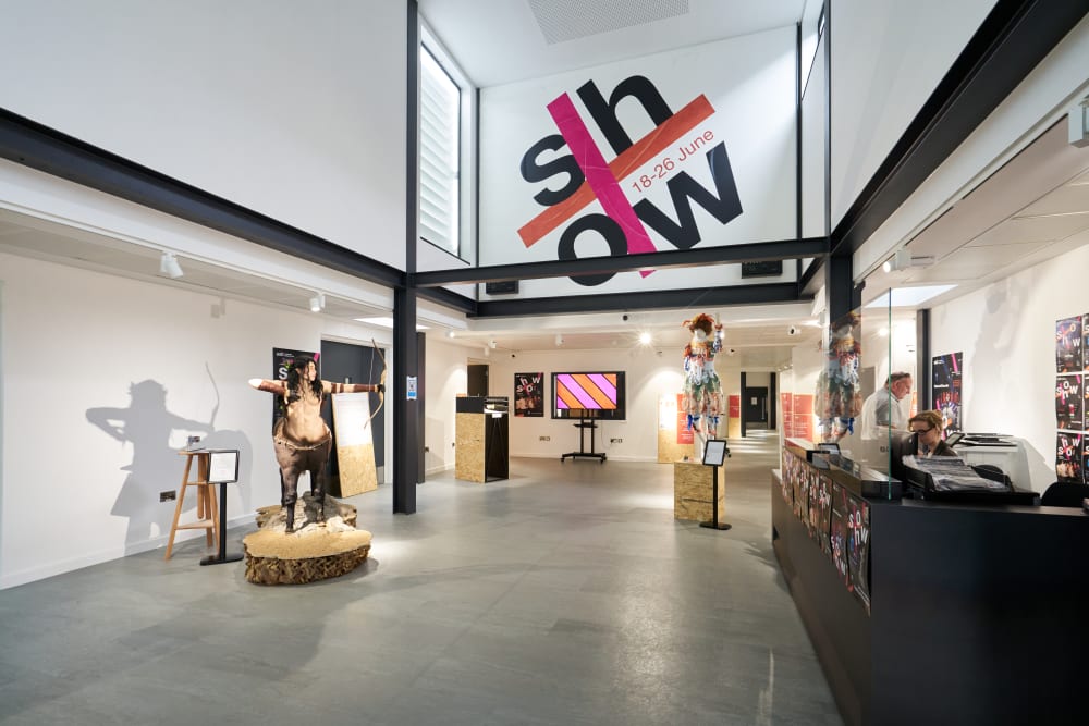 The reception area of Wimbledon College, which has some student artwork displayed. This includes a mannequin wearing colourful clothing and a model of a centaur wielding a bow.