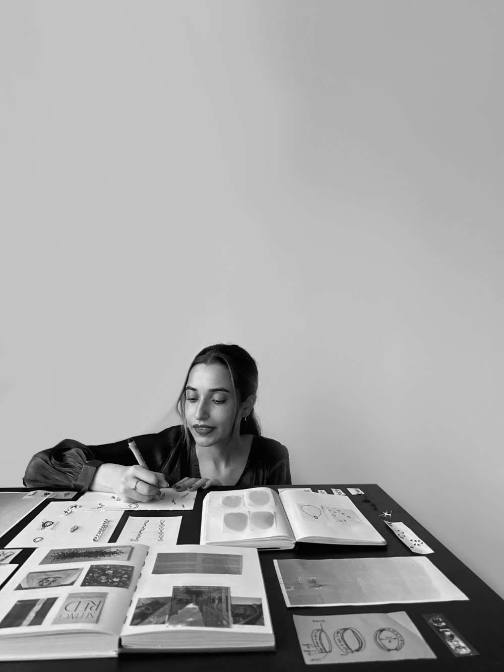 Black and white of Hanan sat working, in front of her are books and research