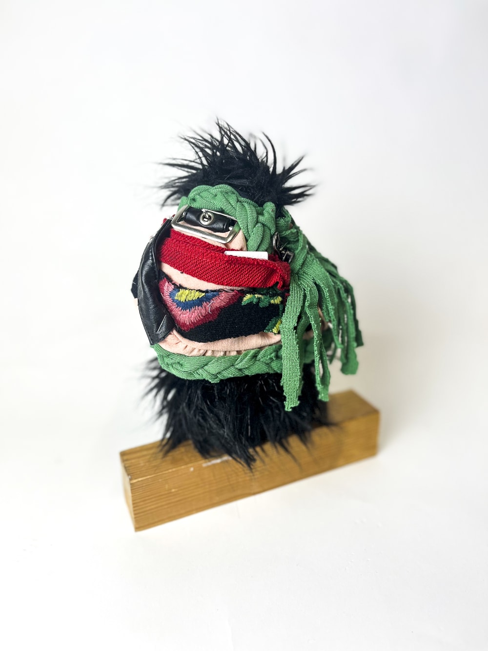 An effigy sculpture made out of textile and wood against a white backdrop.