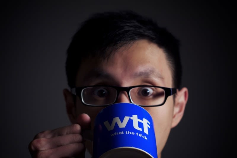 A man holding a mug up and drinking out of it - his eyes are wide. 