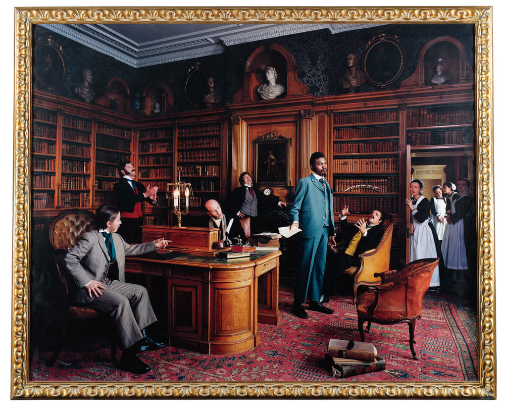 A photo tableau of Yinka Shonibare standing in the middle of an ornate room with various people in maid costumes and suits etc. pandering to him. 