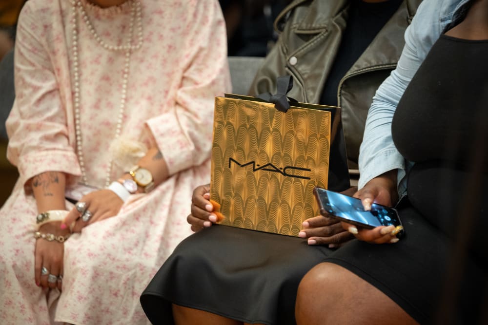 People hands holding MAC gold bag