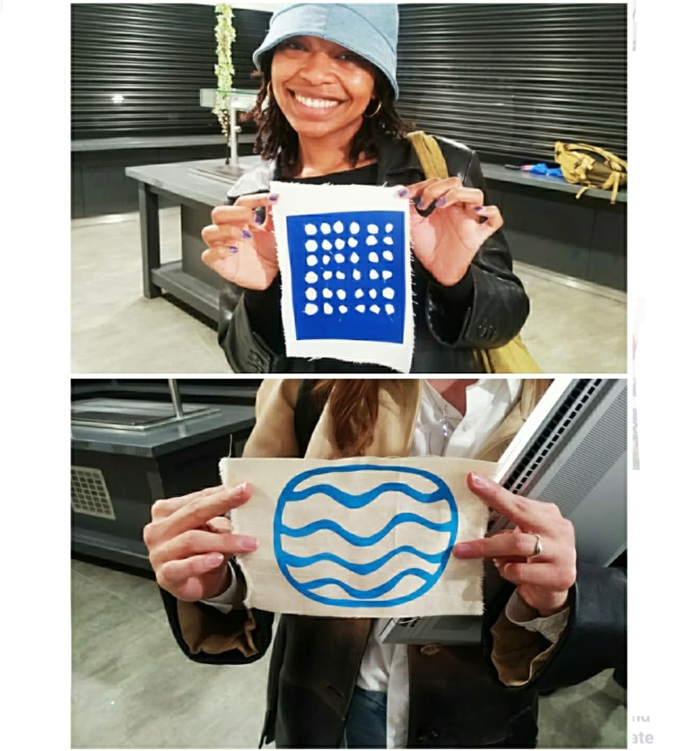 Two students holding their pieces. One is a grid with cut out dots. One is a circle with wavy lines. 