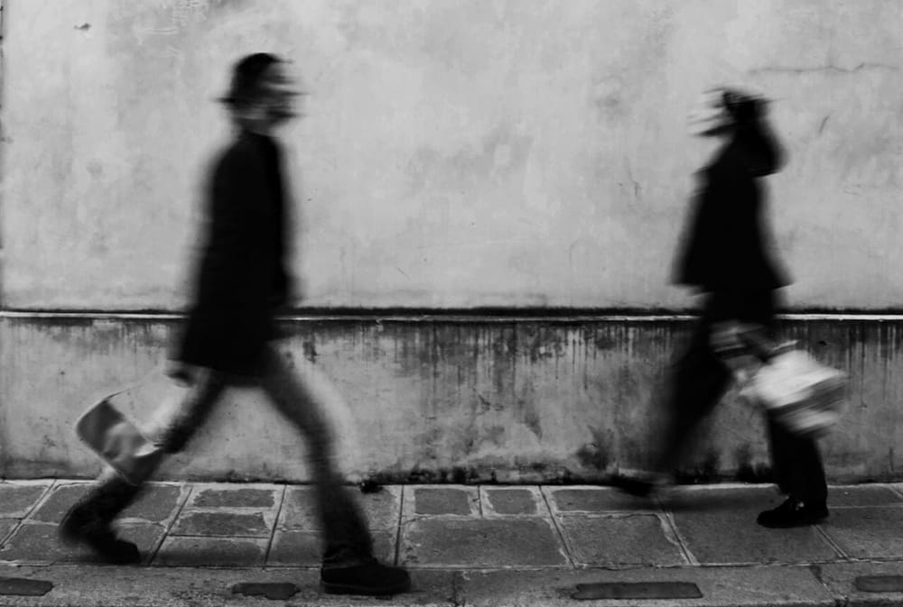 Greyscale photograph of two people walking.