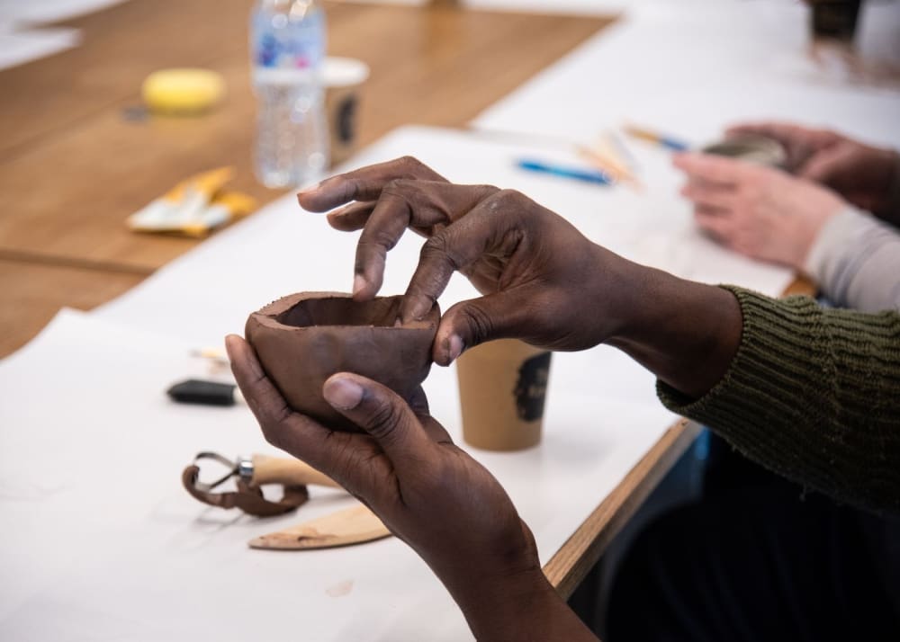 A pair of hands moulding a cup out of clay