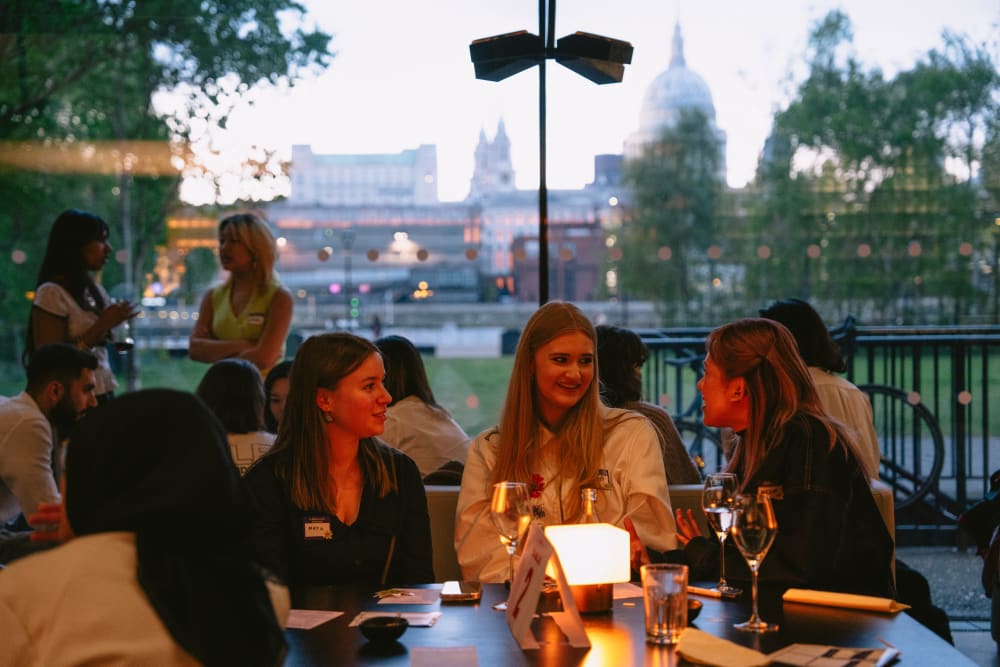 People chatting at a table with St Paul's Cathedral visible in the background