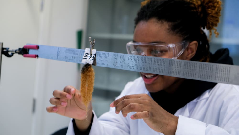 MSc Cosmetic Science student testing haircare products on hair piece