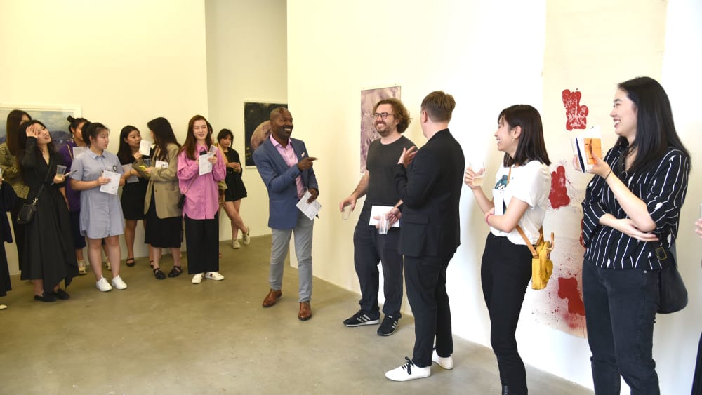 A group of people standing and smiling in a gallery space.