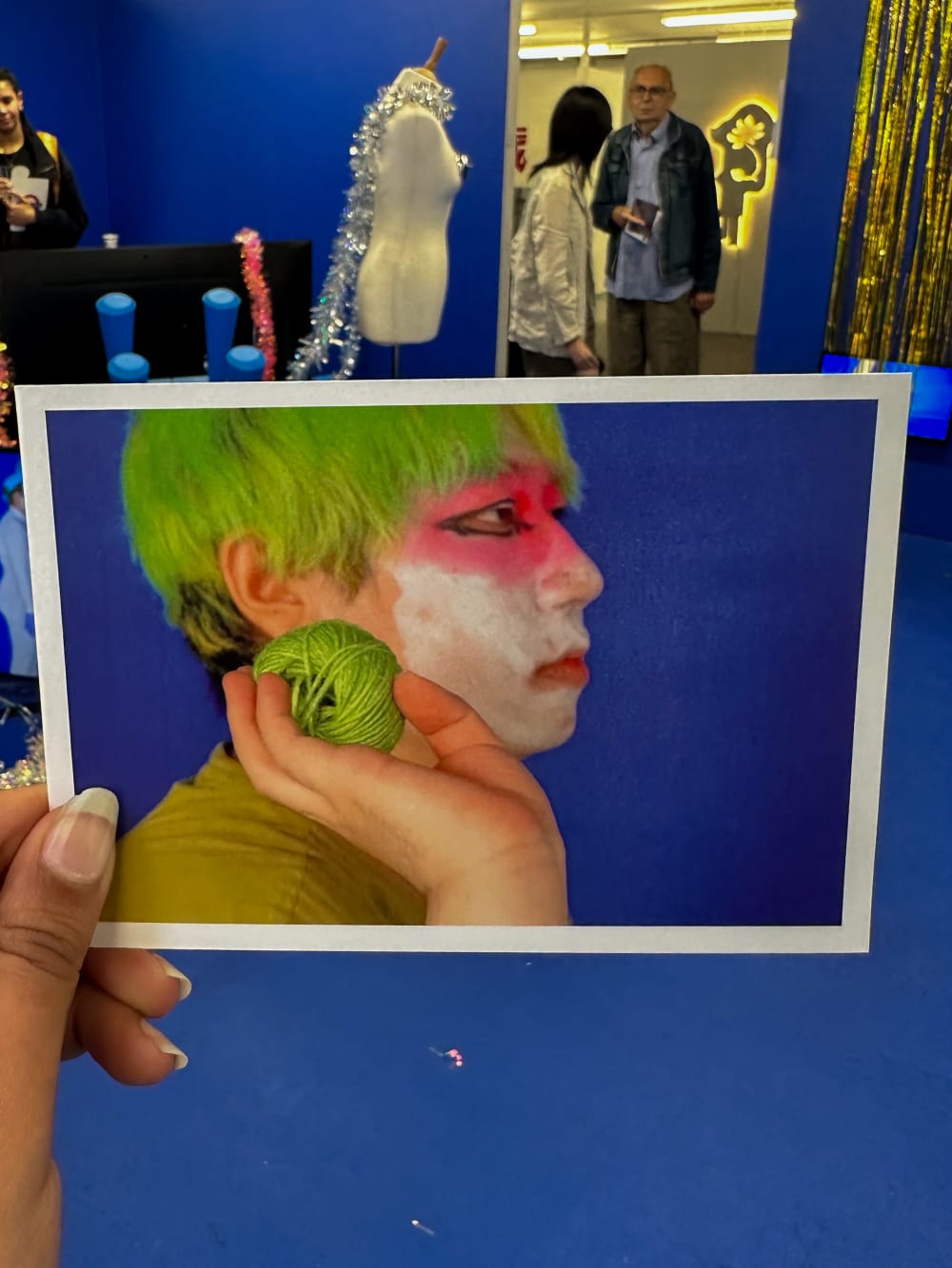 a hand holding a photograph of a person in green and white paint