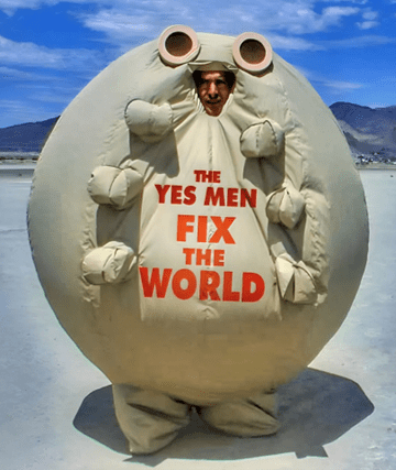 A person inside a giant flea costume, with 'the yes men fix the world' written on it.