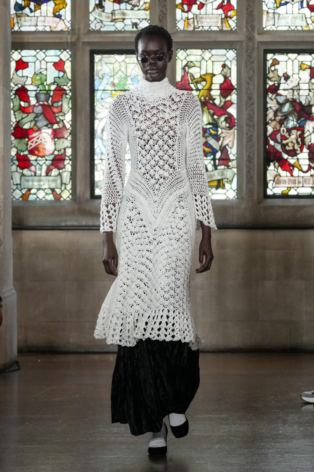 Model on catwalk wearing white crochet dress
