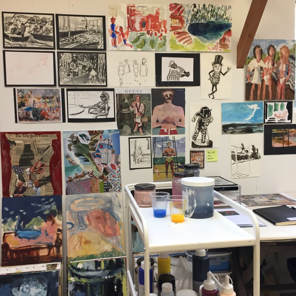 An image of the artists studio featuring a wall of reference images and small paintings.