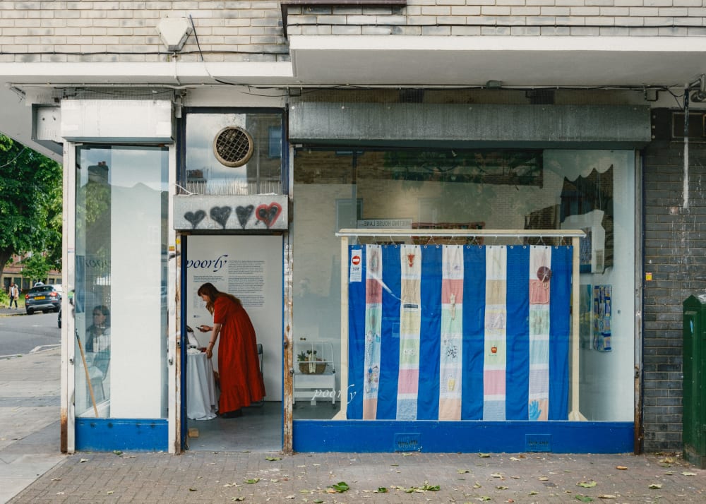 A photo of Phoebe inside of a shop front, which has a white and blue striped canvas displayed in the window