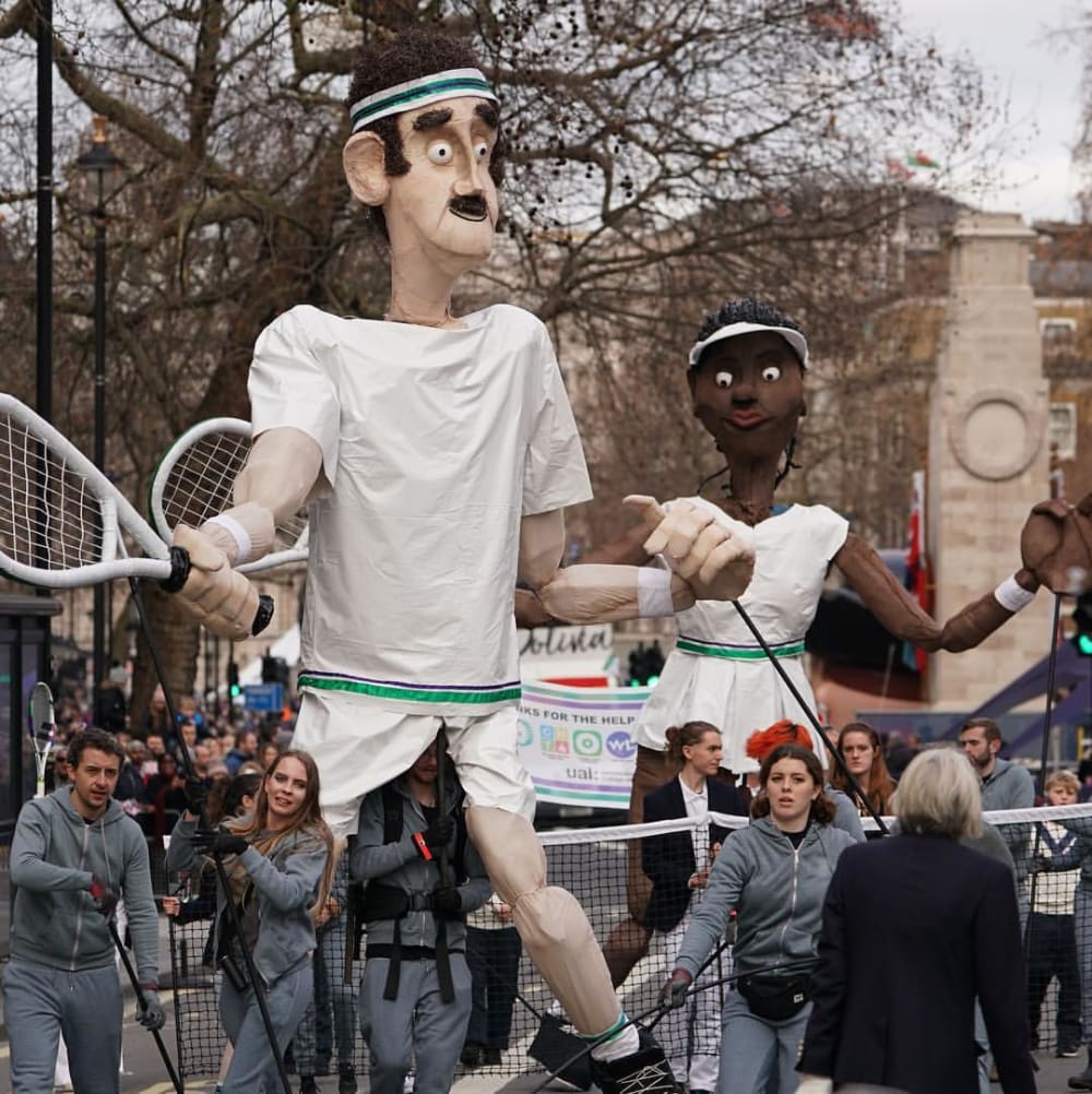 Students carrying the male and female puppets in the parade.