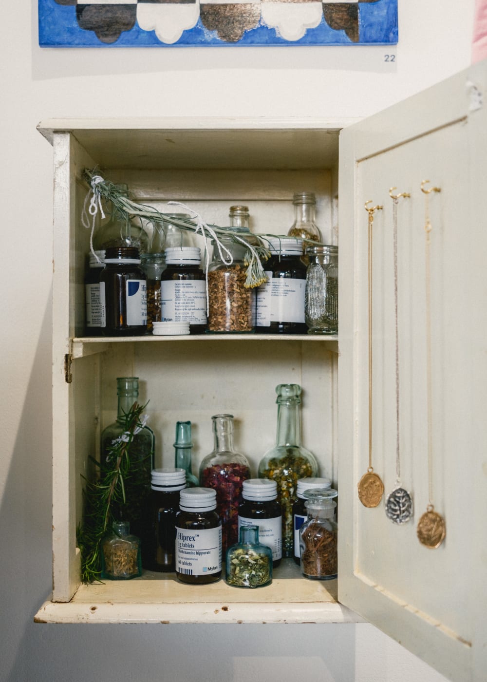 Artwork featuring golden necklaces inside a medicine cupboard made by BA Sculpture student Phoebe Kaniewska