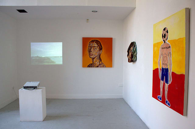 An installation view of three figurative paintings hung on a wall.