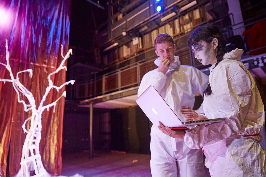 Two people in white plastic suits looking at a laptop screen
