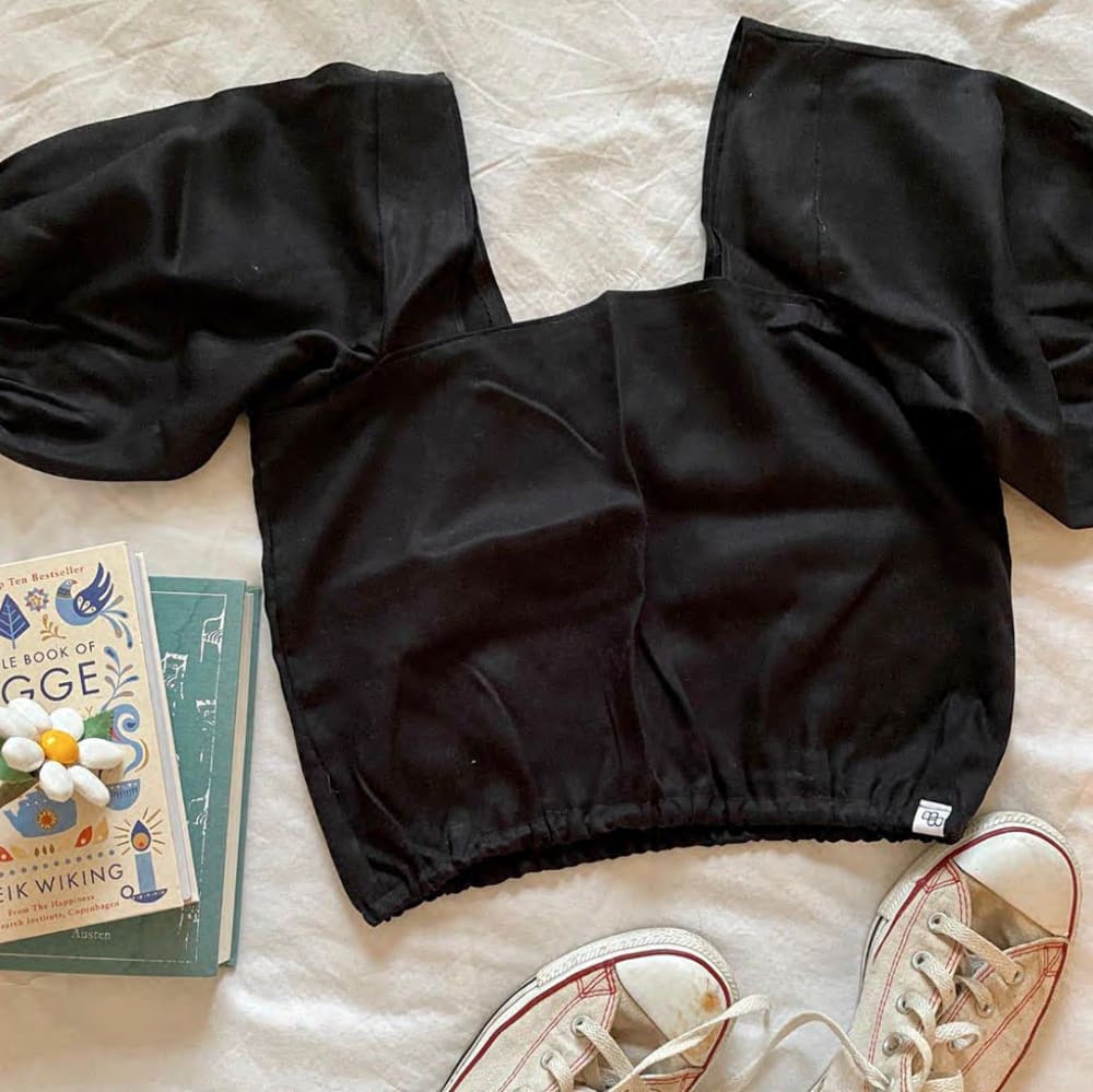 Black top laid flat with converse and a selection of books