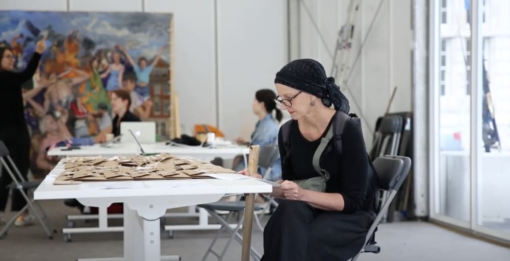 A woman sitting at a table in an art studio