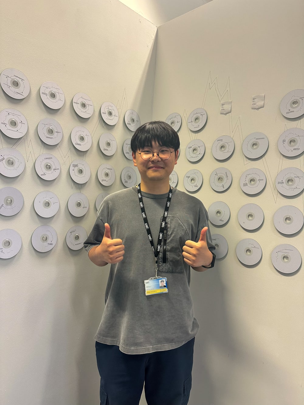 an artist in front of a wall of hanging cds