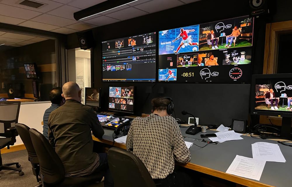 Students sit by a range of TV monitors.
