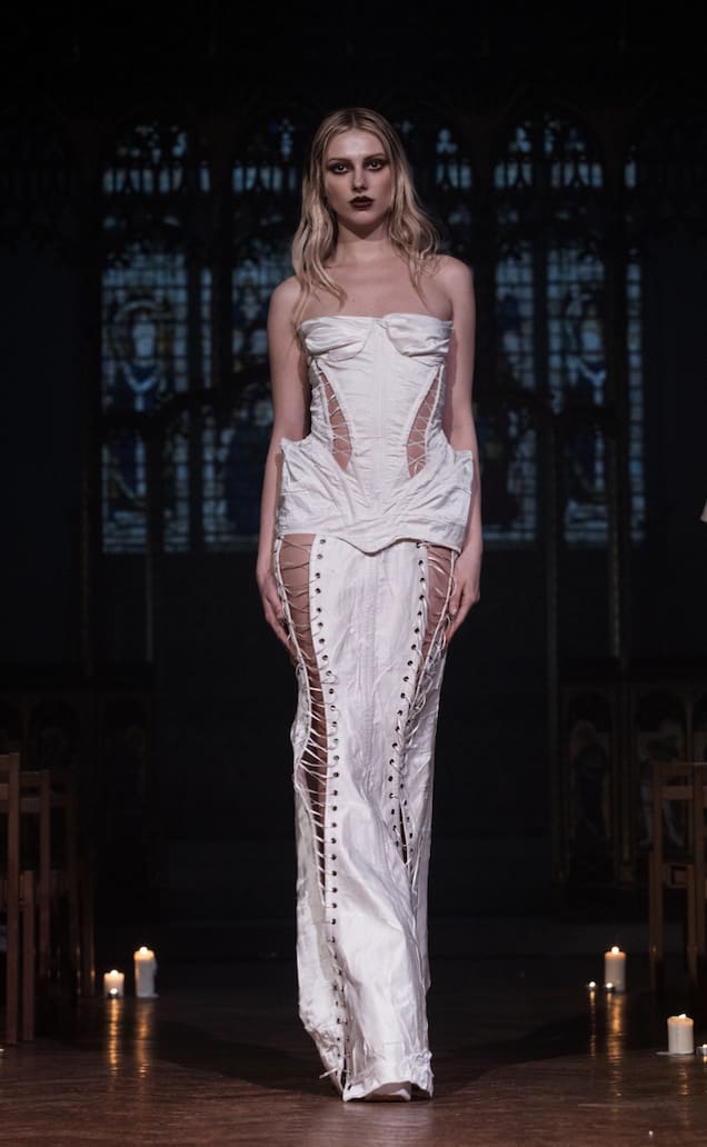 Model on catwalk wearing a white corset dress